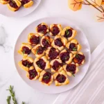puff pastry squares with cranberry sauce and brie cheese on a white plate