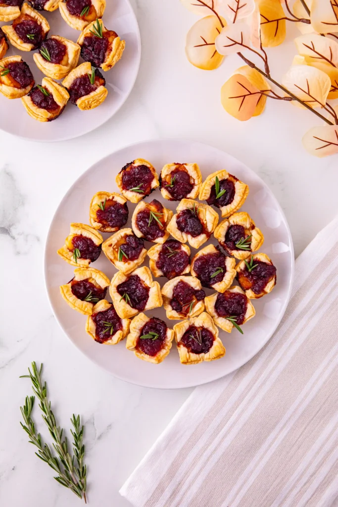 puff pastry squares with cranberry sauce and brie cheese on a white plate