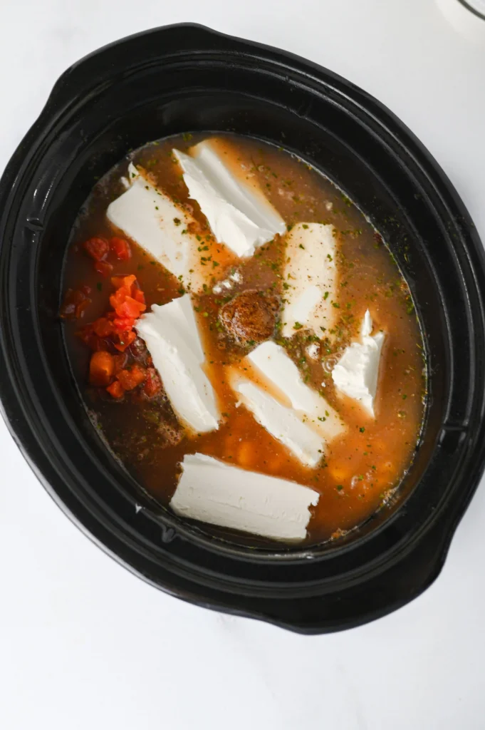 chicken, beans, tomatoes, spices and corn in a crockpot with chicken broth and cream cheese chunks