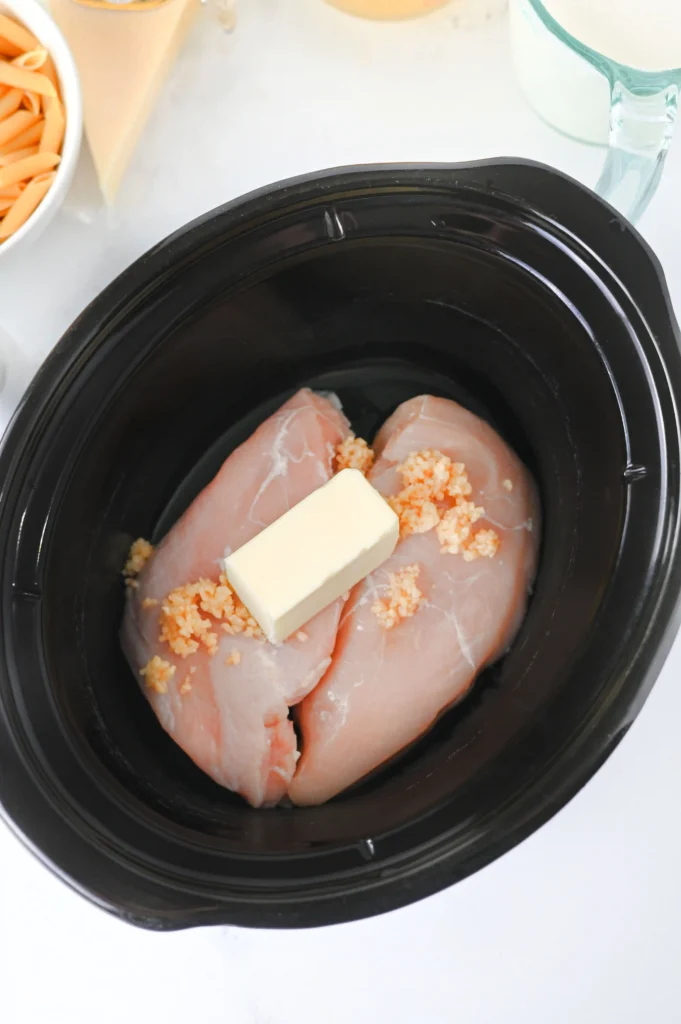 a crockpot with chicken breasts, butter and garlic