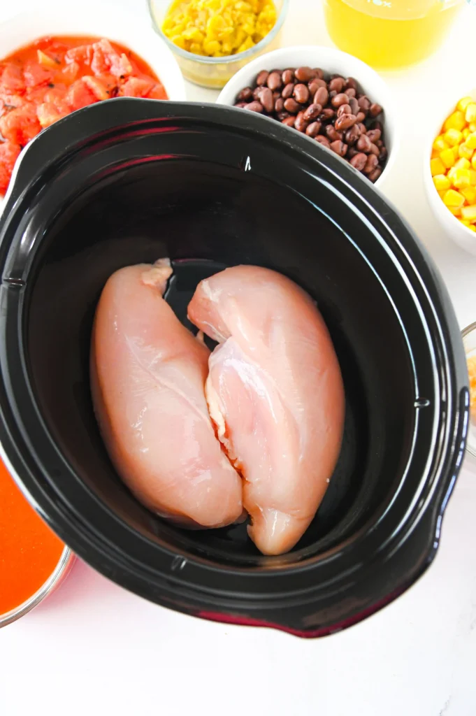 a crock pot with chicken breasts inside